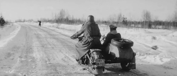 The distant figure of Lazarev in German battledress stops a a motorcycle and sidecar in an ambush.